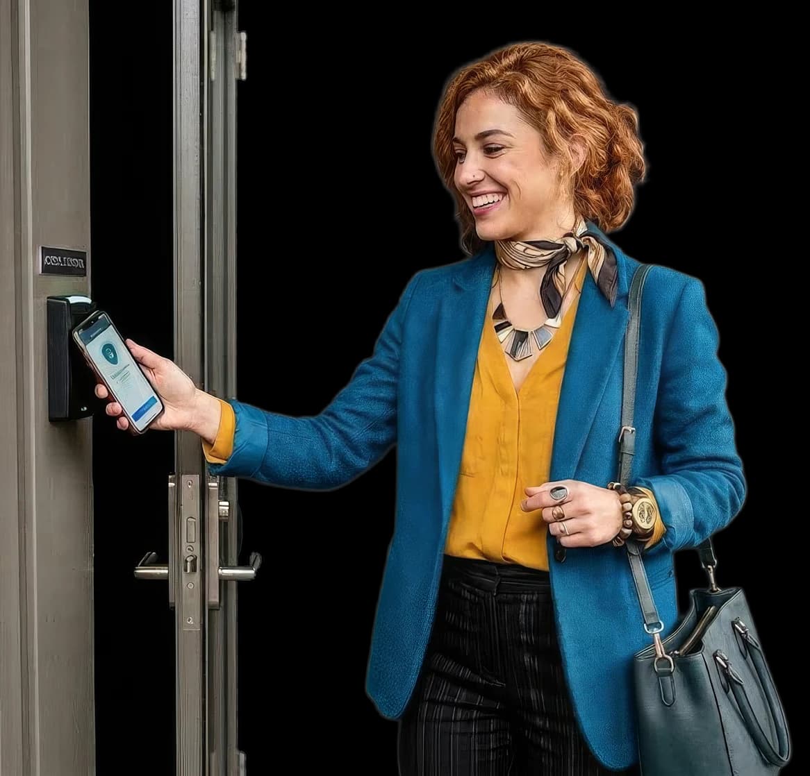 Nasmiješena žena u plavom sakou prislanja telefon s digitalnim ključem na zidni NFC čitač pokraj vrata.